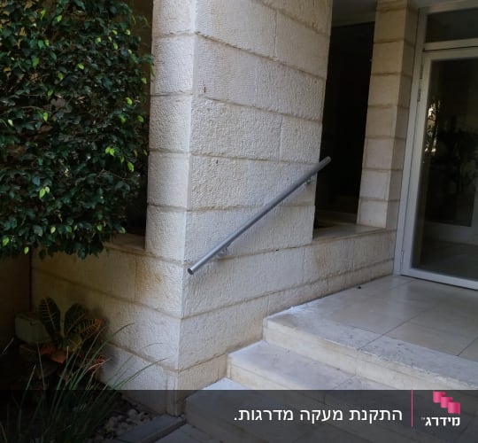 מעקה מתכת ליד דלת זכוכית במסגרת אלומיניום